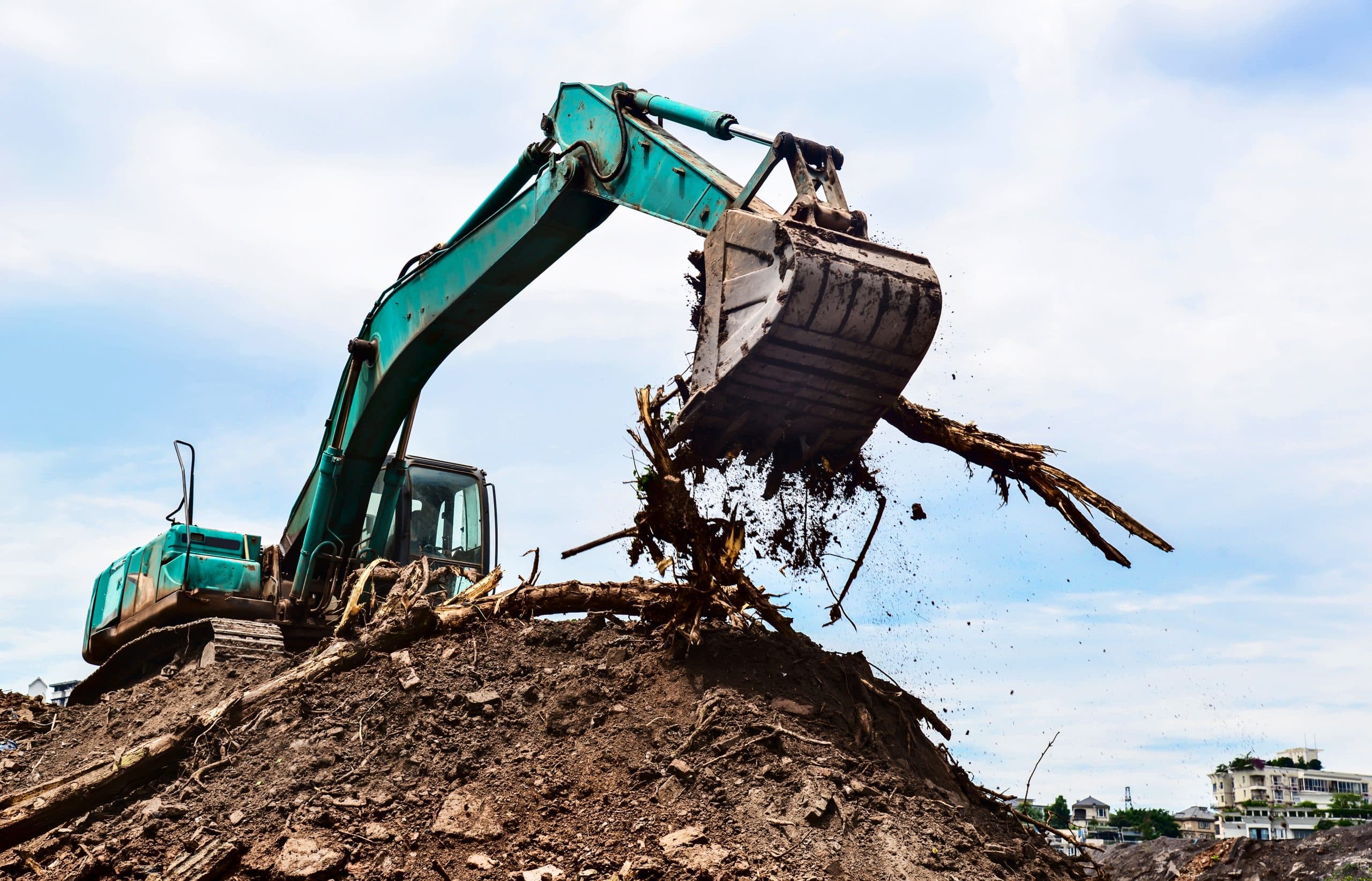 Excavator mid-demolition of a structure with dust in the air